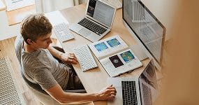 SEO Melbourne 2 UI UX designer creating responsive website mockups on multiple laptops in a digital workspace.